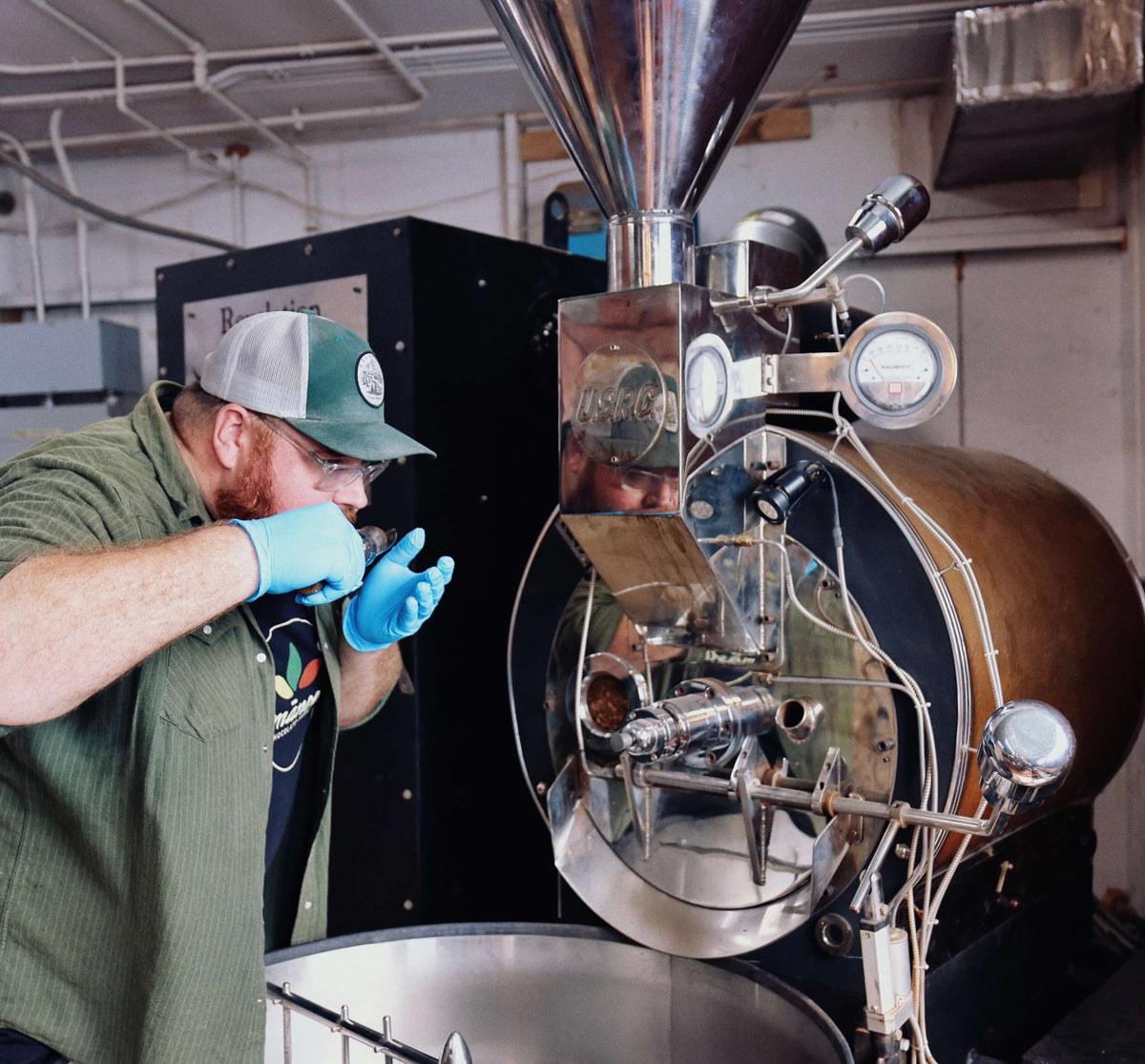 Person operating a coffee roasting machine in a factory setting