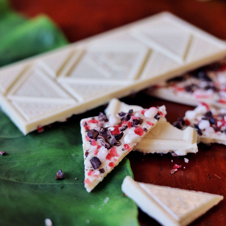 image of broken peppermint crunch white chocolate bar on table with tropical leaves