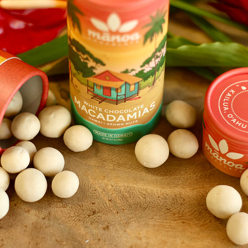 Image of white chocolate macadamia nuts scattered on table next to colorful tube package