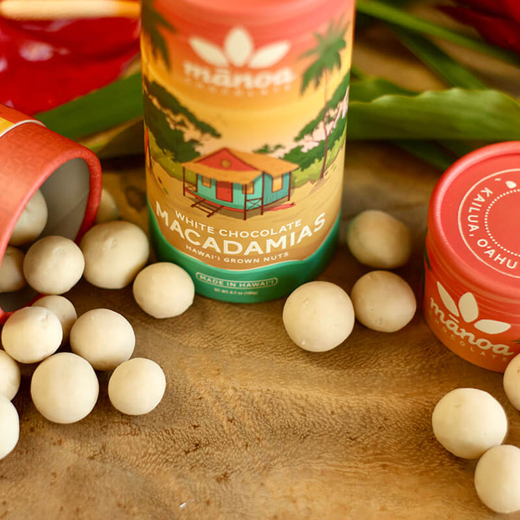 Image of white chocolate macadamia nuts scattered on table next to colorful tube package
