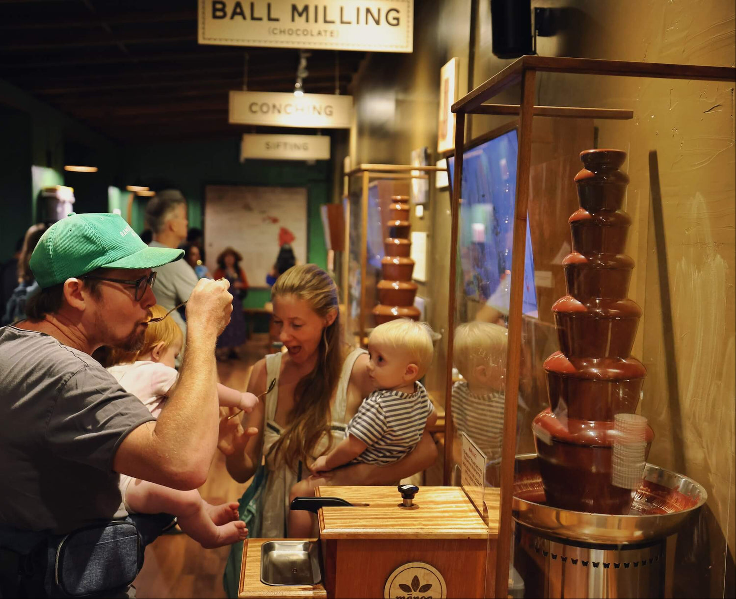 image of a man tasting chocolate from a chocolate fountain with his family