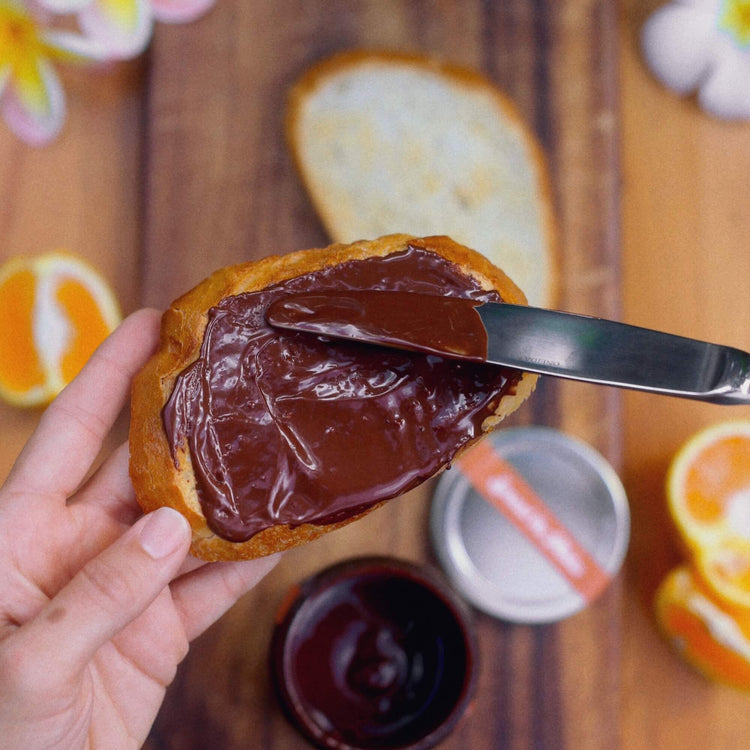 Image of a person spreading dark hazelnut spread on toast