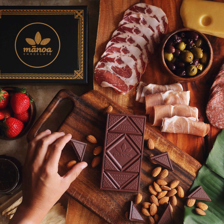 Image of gift box with gold Manoa logo sitting among charcuterie board