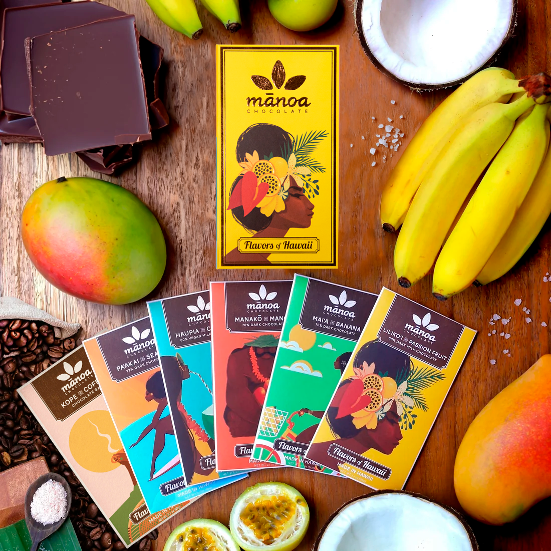 Image of six brightly-colored chocolate bars with bright yellow gift box and tropical fruits