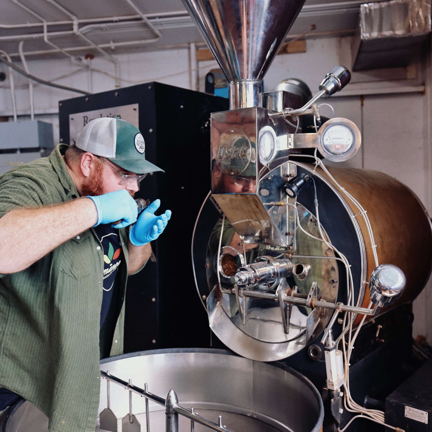 Person operating a coffee roasting machine in a factory setting