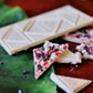 image of broken peppermint crunch white chocolate bar on table with tropical leaves 