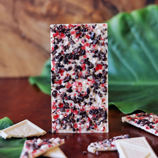 image of peppermint crunch white chocolate bar on table with tropical leaves and broken bars