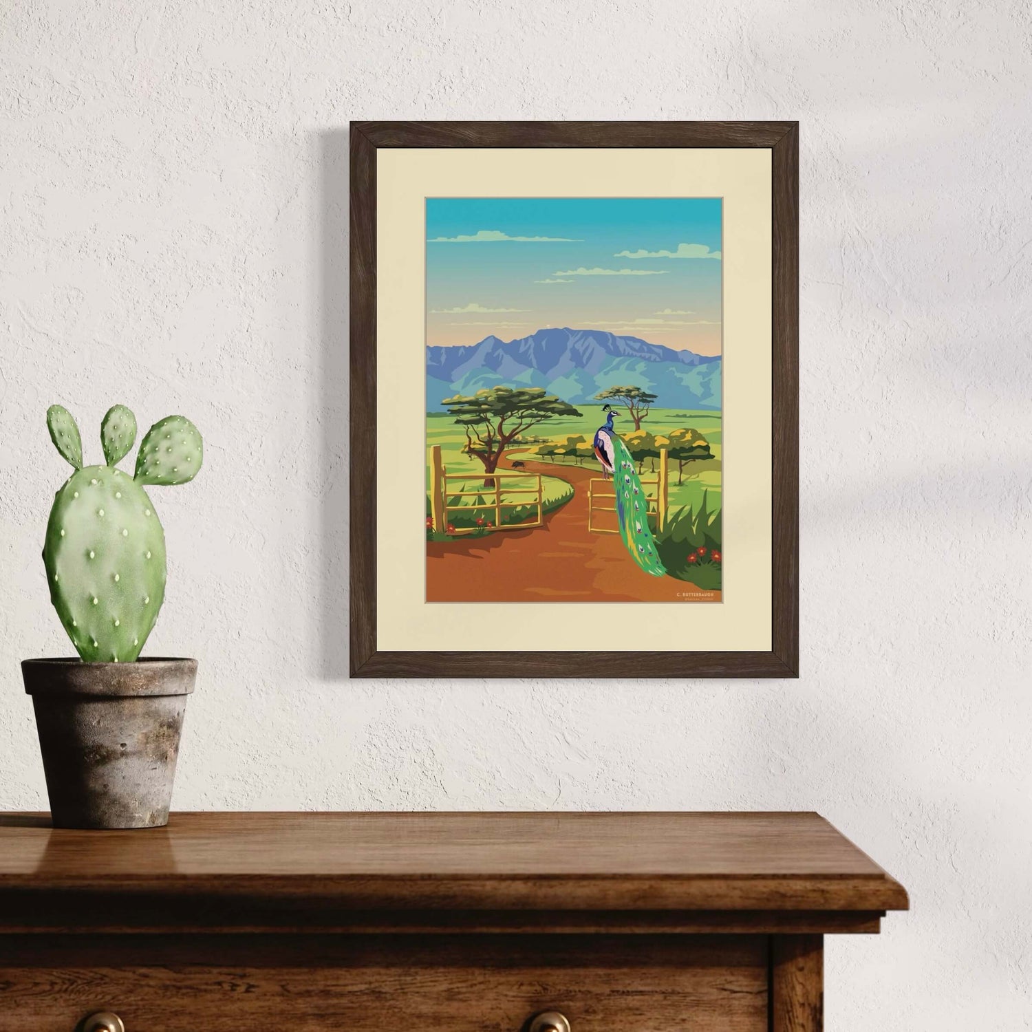 image of kamananui art print framed and hanging on a wall above a dresser with a cactus plant sitting beside it