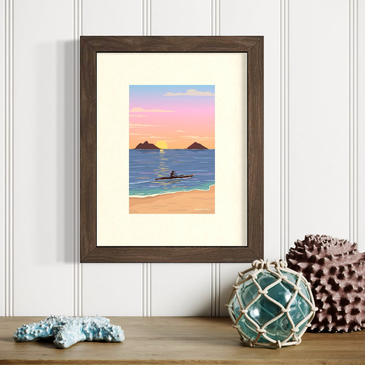 Framed artwork of a beach scene with a kayak at sunset, displayed on a wall.
