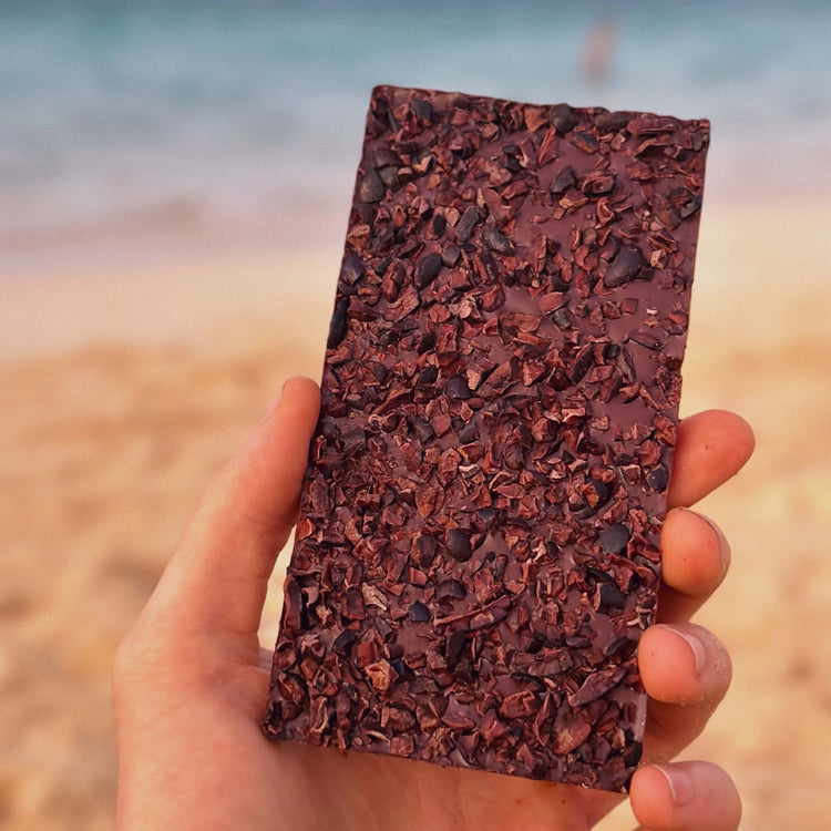 Image of hand holding unwrapped breakfast bar showing the back covered in cacao nibs