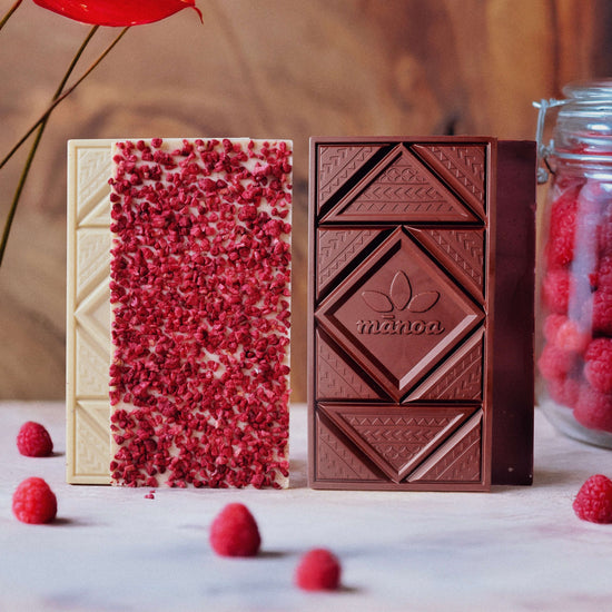 raspberry white and dark chocolate bars on a marble counter with raspberries and flower