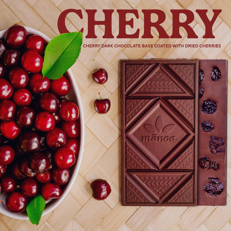 Image of dark chocolate bars with dried cherries on the back, next to a bowl of fresh cherries
