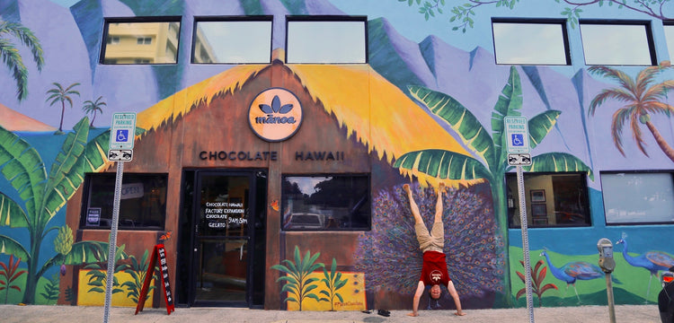 Image of man doing handstand in front of Mānoa Chocolate storefront