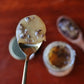 Spoonful of raw honey and nibs on a red wood background