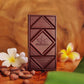 Image of chocolate bar on wooden table with flowers, cocoa beans, and banana leaves