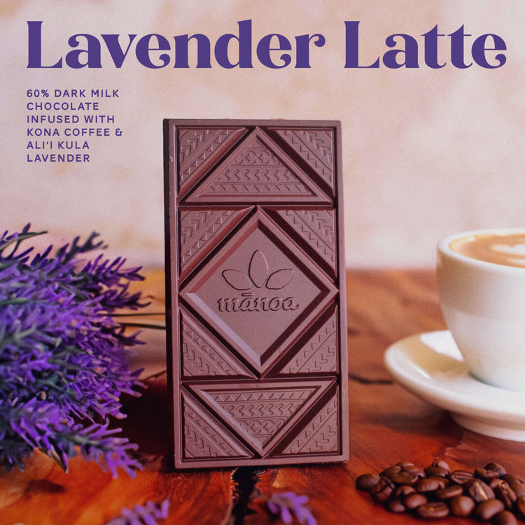 Image of a lavender latte chocolate bar sitting on wood table with lavender bouquet, coffee beans, and fresh brewed cup coffee