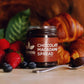 Image of Chocolate Macadamia Spread jar with fresh fruit in the foreground and croissants in the background.