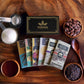 Image of 6 chocolate bars sitting among a gift box, cacao beans, sugar and nibs