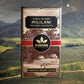 Image of Mililani chocolate bar in brown, natural-looking packaging, over landscape photo of farmlands