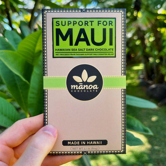 Image of a hand holding a chocolate bar with text "Support for Maui Hawaiian Sea Salt Dark Chocolate - Net Proceeds From This Bar Support Maui Disaster Relief"