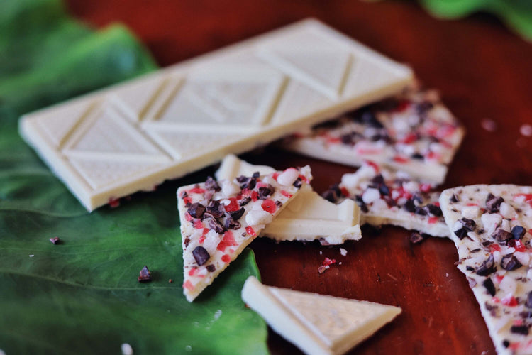 image of peppermint crunch white chocolate bar with broken pieces on table with green leaf decoration