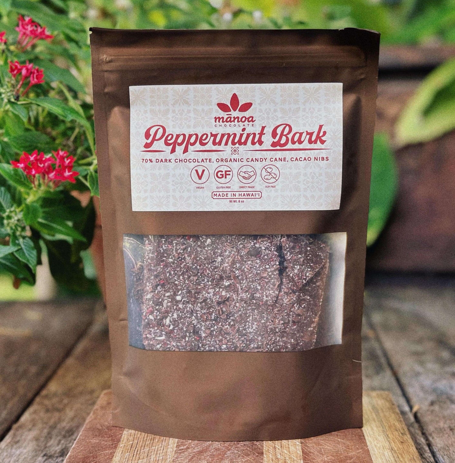Manoa Peppermint Bark package on a wooden surface with plants in the background