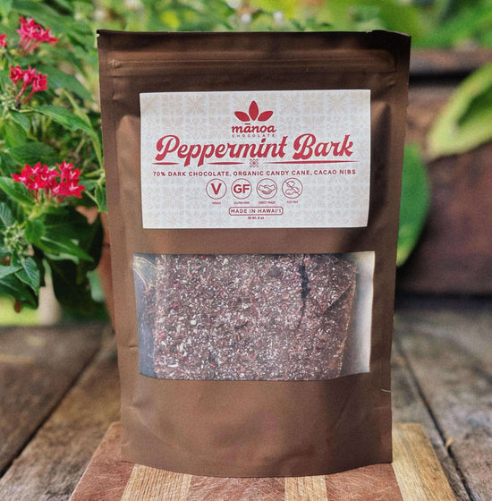 Manoa Peppermint Bark package on a wooden surface with plants in the background