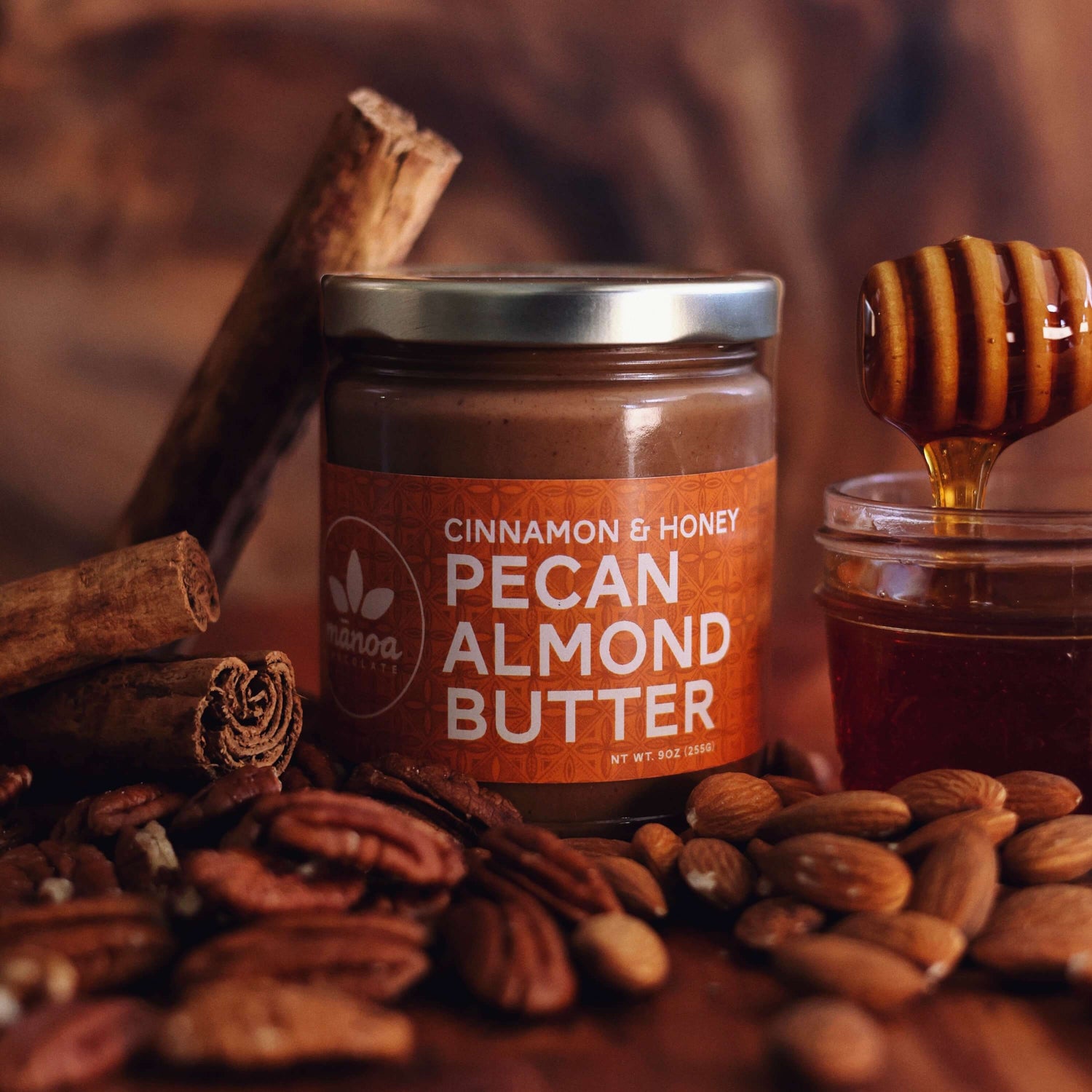 Jar of pecan almond butter sitting among nuts and jar of honey