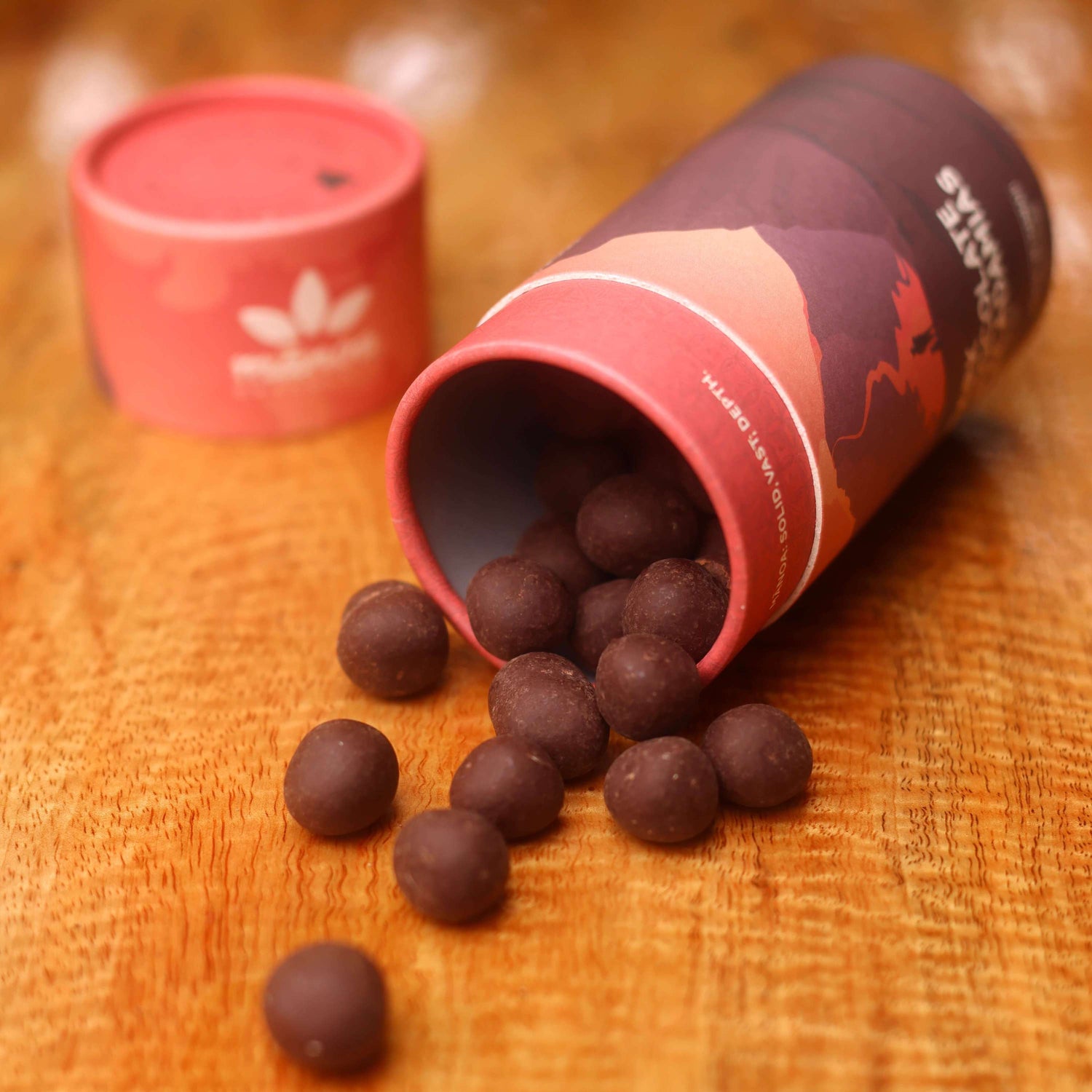 Image of tube with chocolate-covered macadamia nuts spilling out onto table