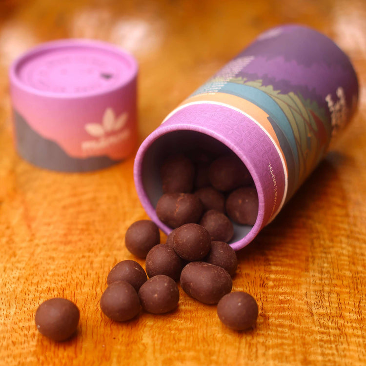 Image of tube with rum chocolate macadamias spilling over onto table