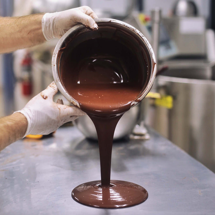 Image of liquid chocolate being poured onto a stainless steel table
