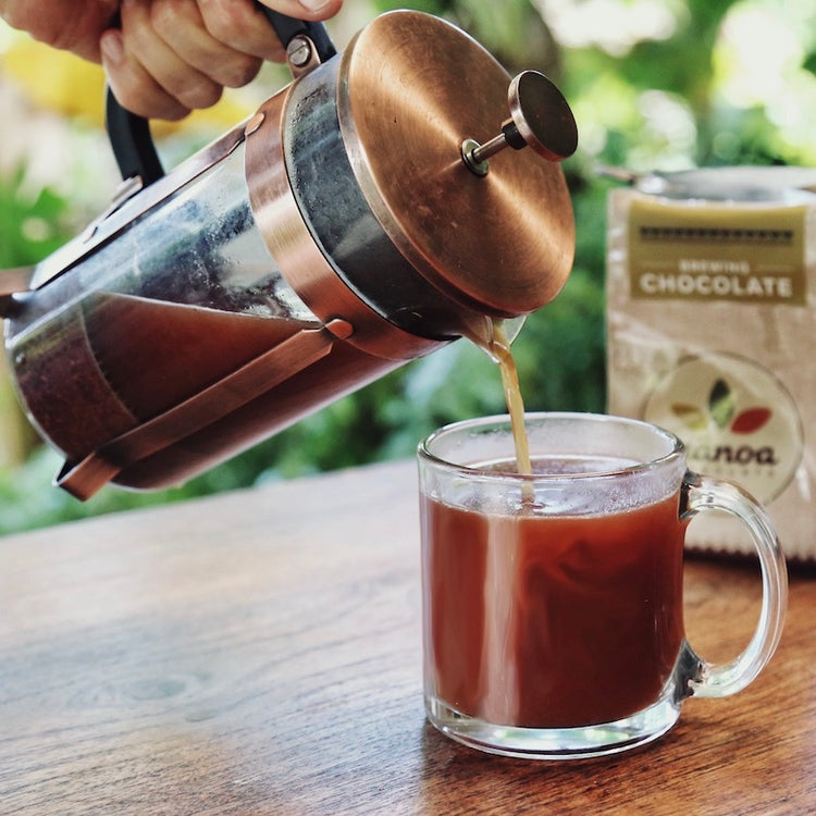 Image of person pouring brewing chocolate from a french press into a mug