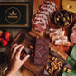 Image of gift box with gold Manoa logo sitting among charcuterie board